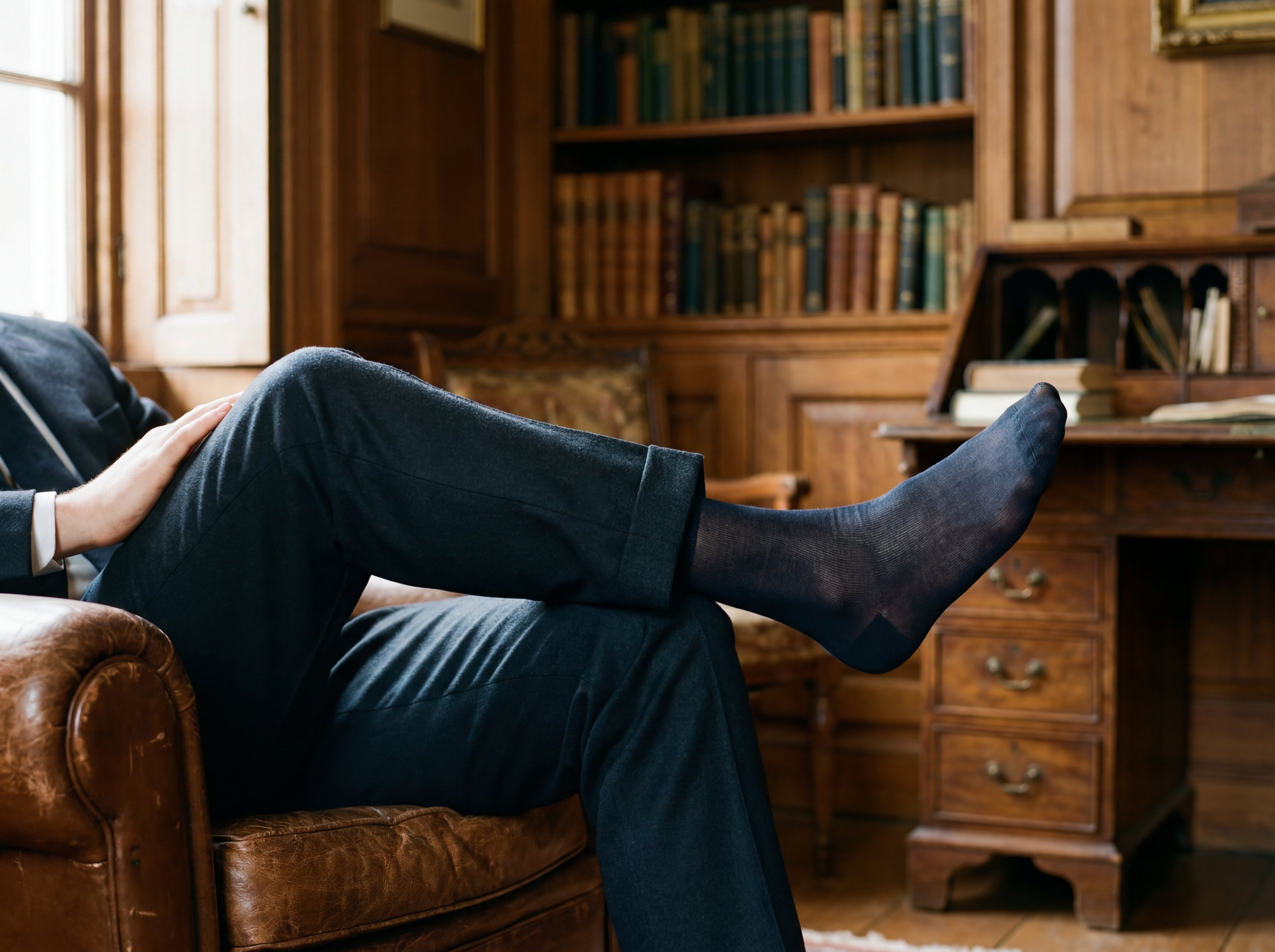 Elegant gekleideter Mann sitzend mit langen, feinen StrĂŒmpfen und klassischen Schuhen