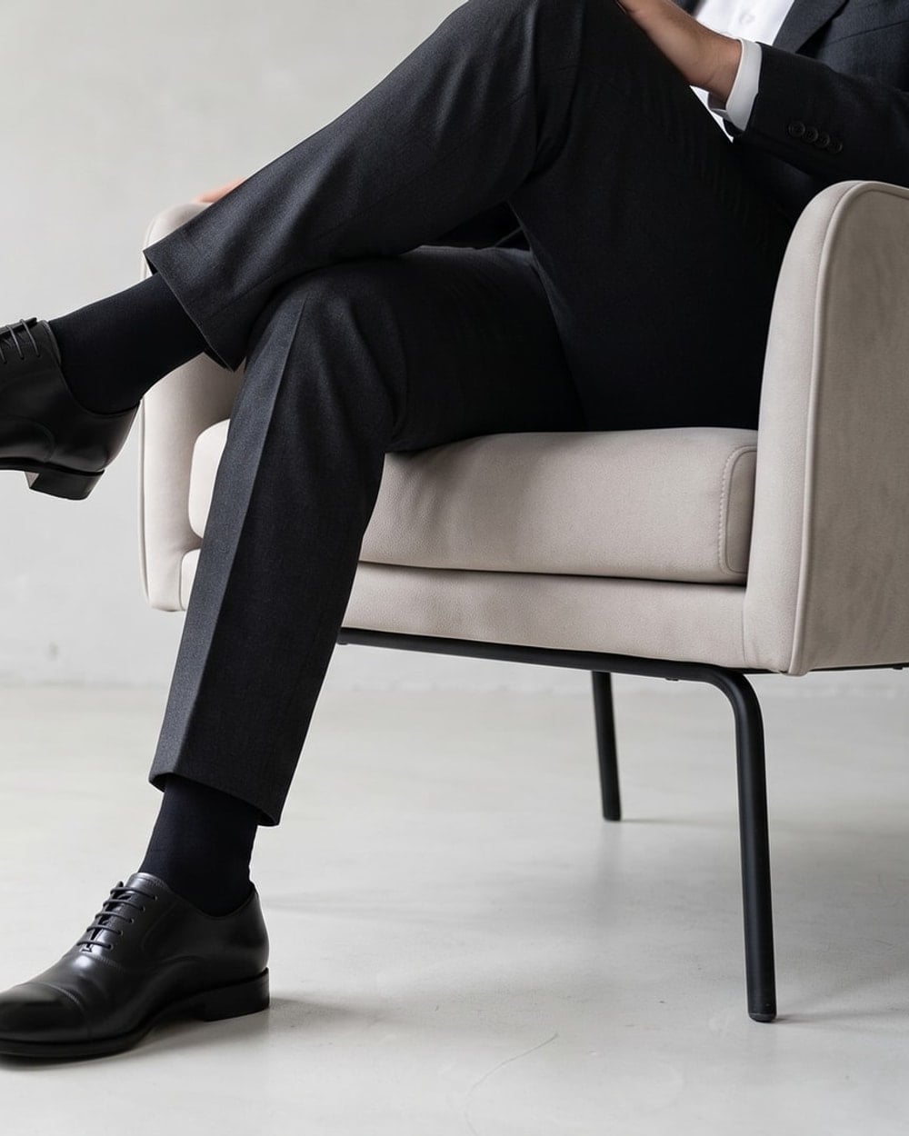 Mann im dunklen Anzug sitzend mit langen schwarzen Baumwollsocken unter der Hose